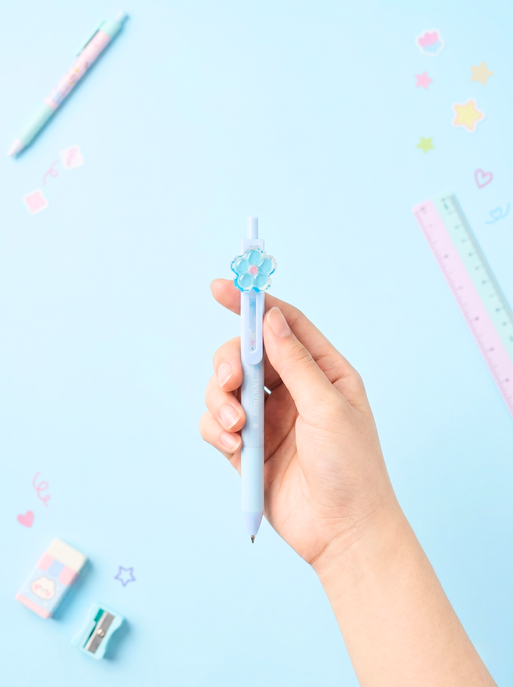 Hand holding a light blue pen with decorative elements on a light blue background
