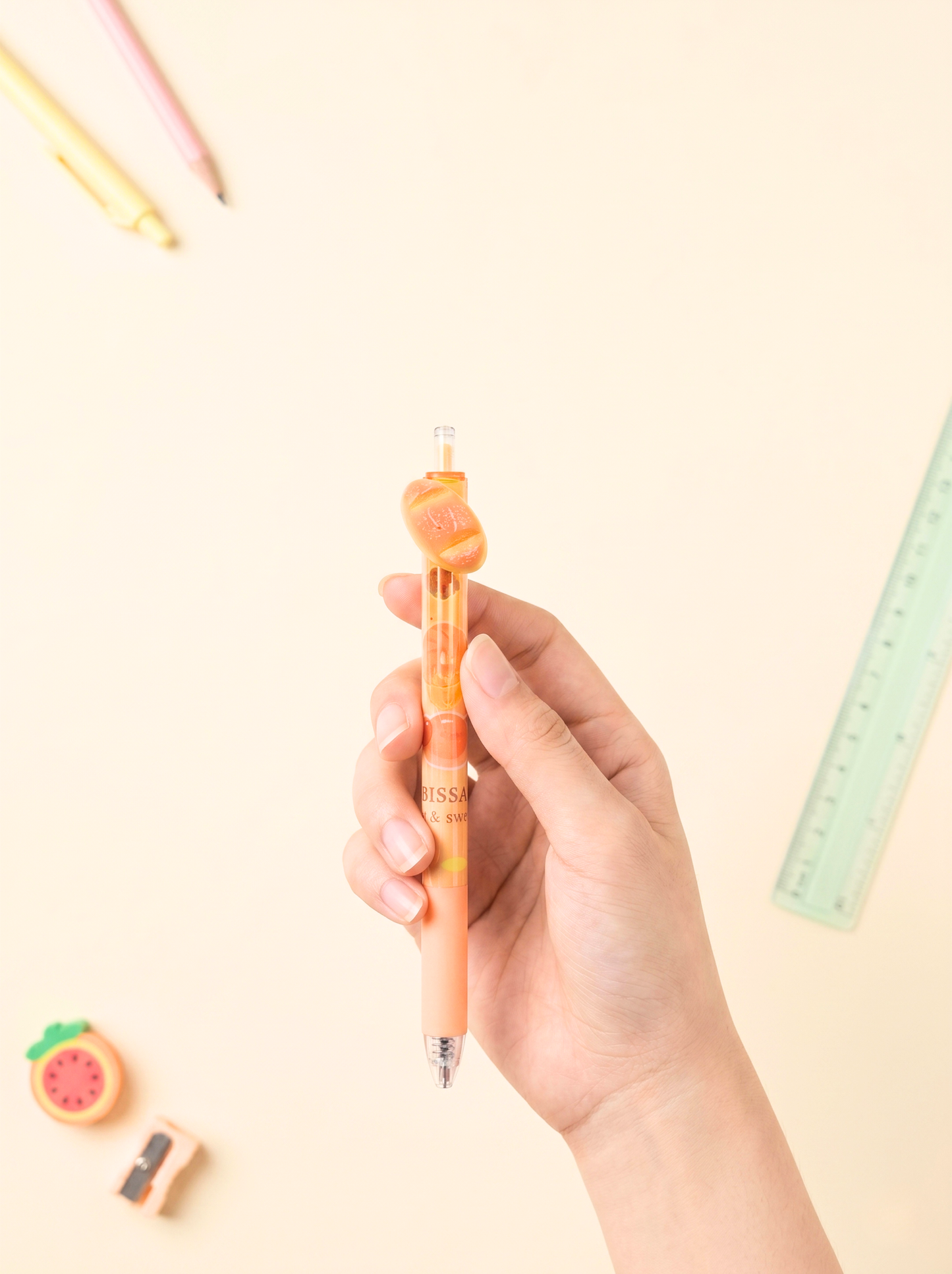 Hand holding a colorful pen with stationery items on a light background