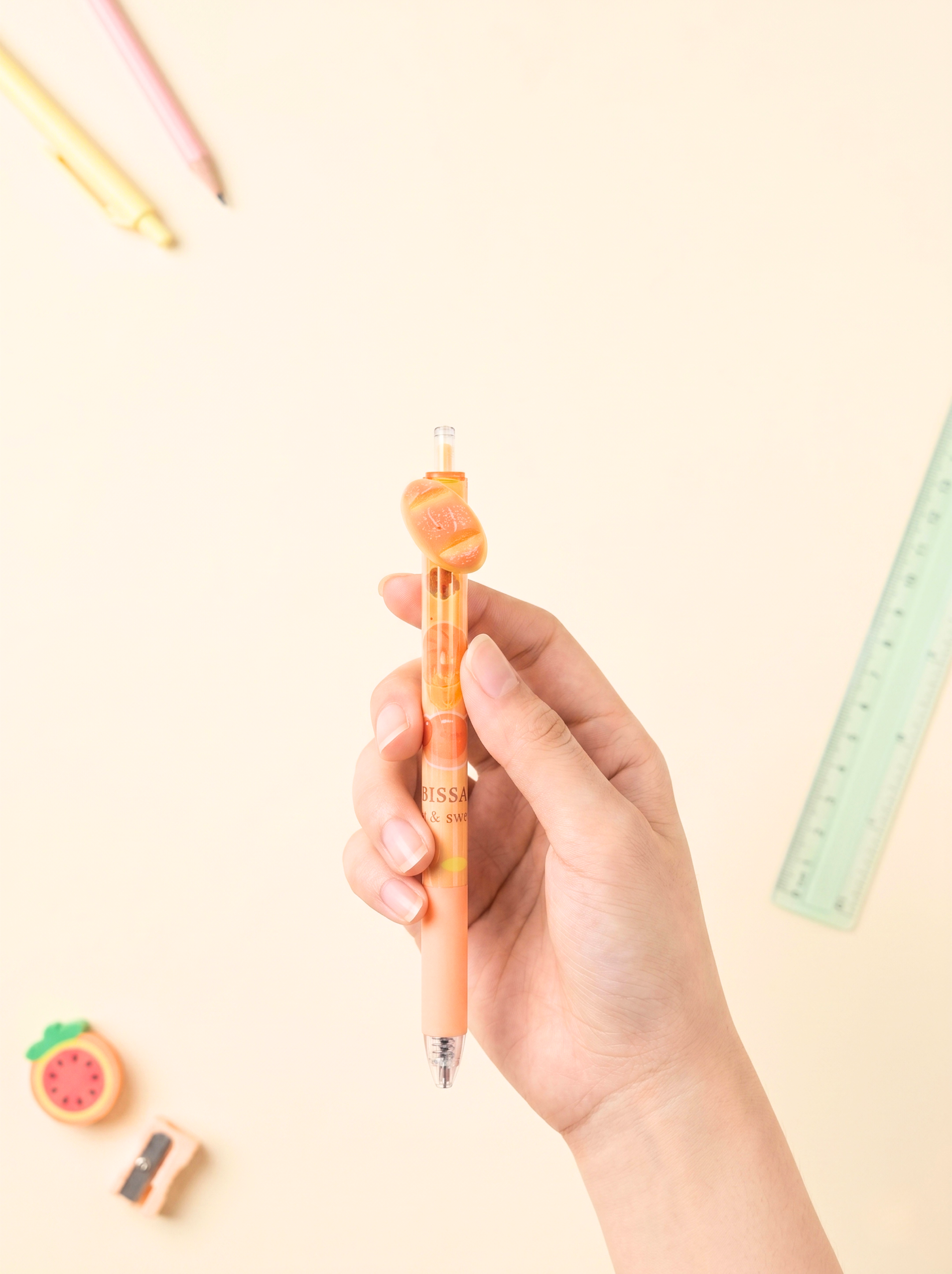 Hand holding a colorful pen with stationery items on a light background