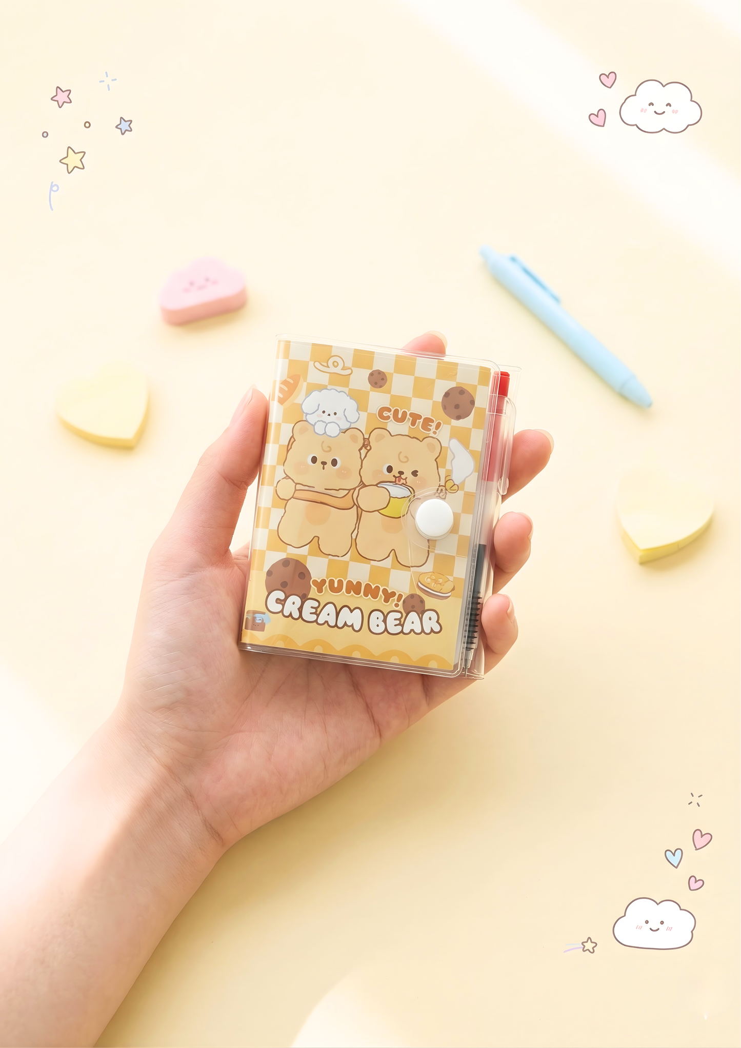 Hand holding a small notebook with cartoon bear design on a yellow background