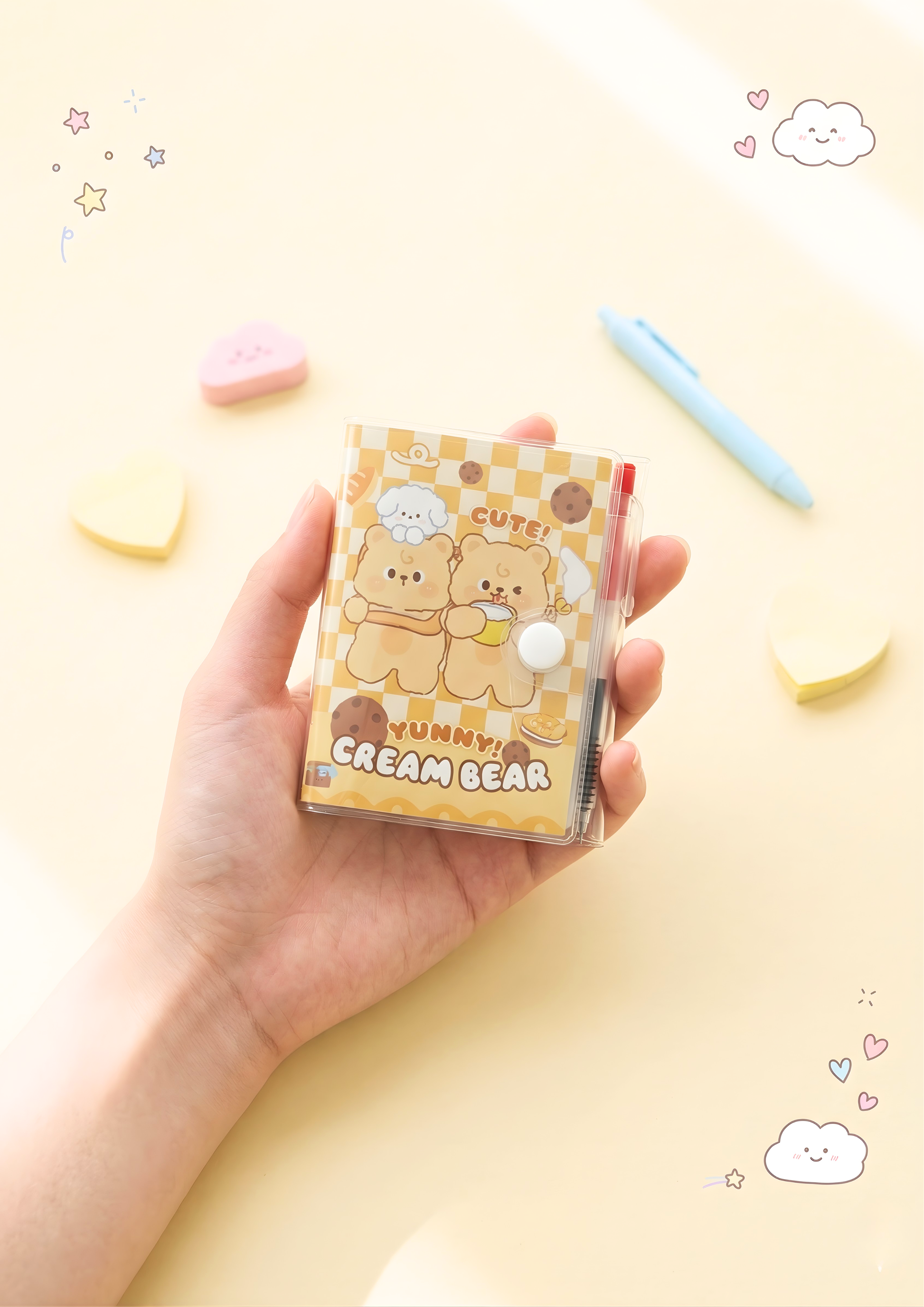 Hand holding a small notebook with cartoon bear design on a yellow background