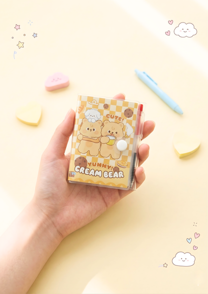 Hand holding a small notebook with cartoon bear design on a yellow background