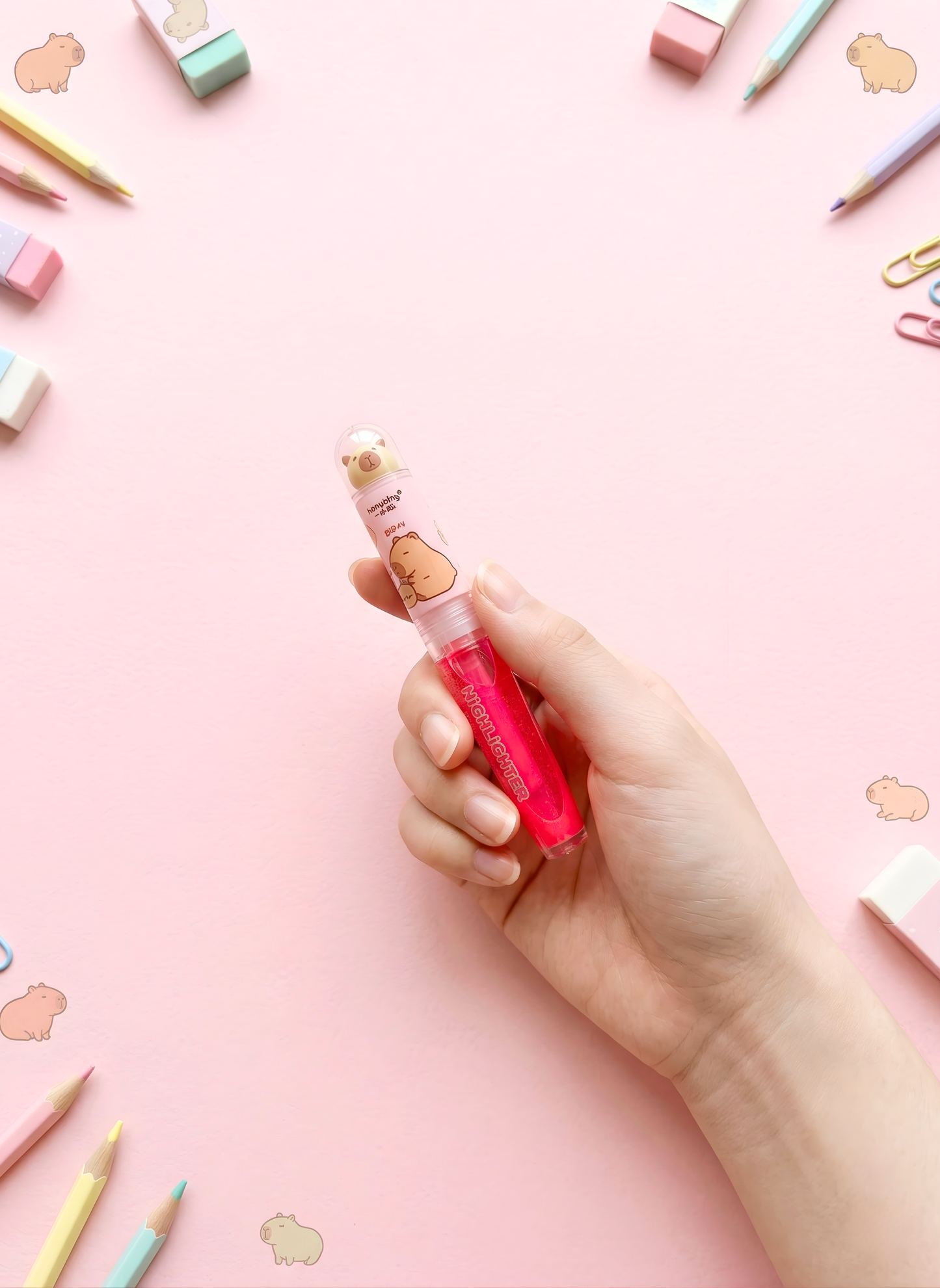 Hand holding a pink lip gloss with a cartoon character on a pink background