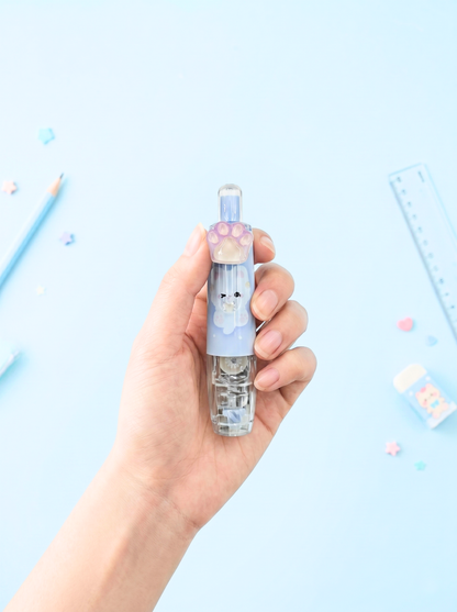 Hand holding a small transparent container with a blue lid featuring a cartoon face on a light blue background.