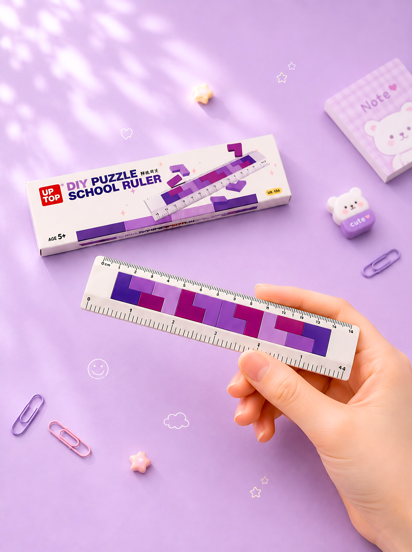 Hand holding a colorful ruler with packaging labeled 'DIY Puzzle School Ruler' on a purple background.