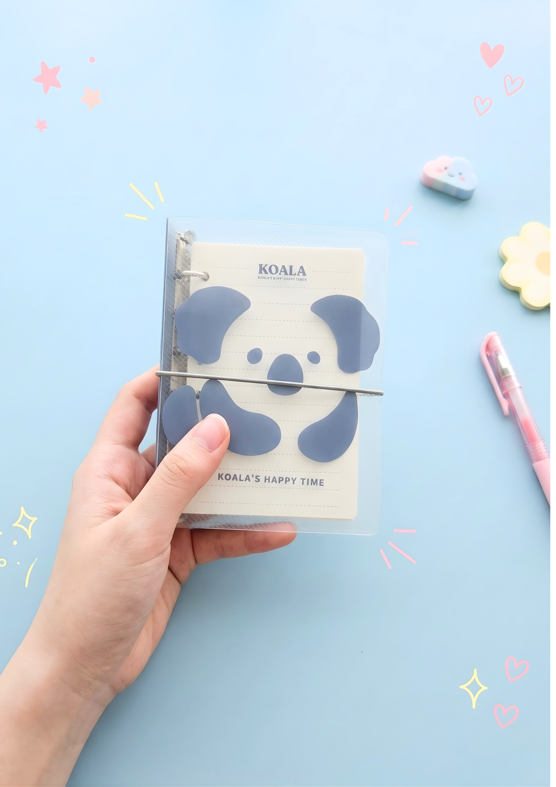 Hand holding a notebook with a koala design on a light blue background