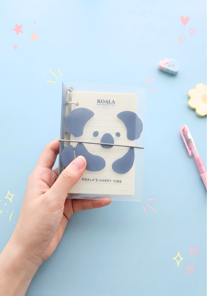 Hand holding a notebook with a koala design on a light blue background