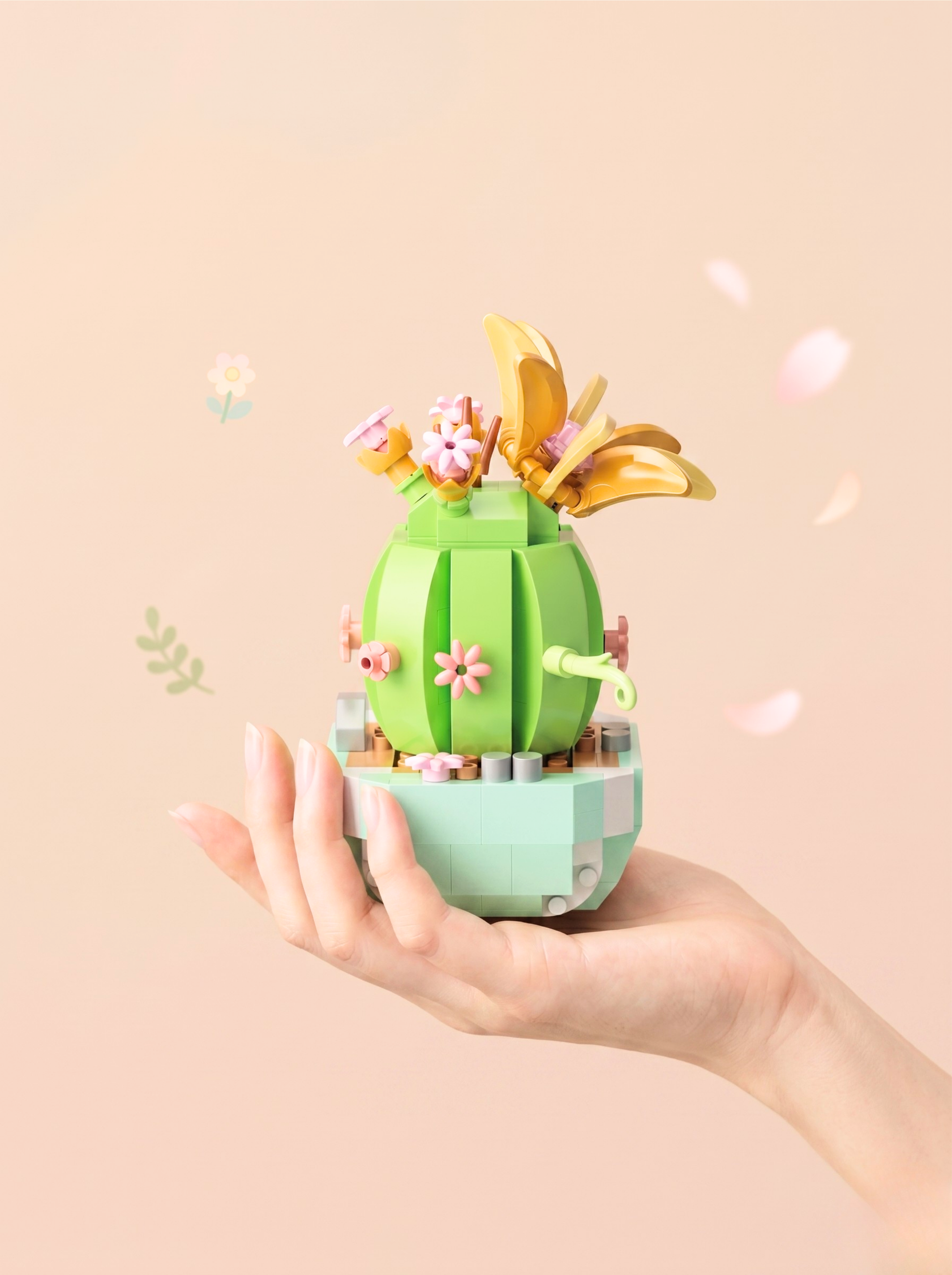 Hand holding a small green cactus-like toy with flowers and gold leaves on a beige background