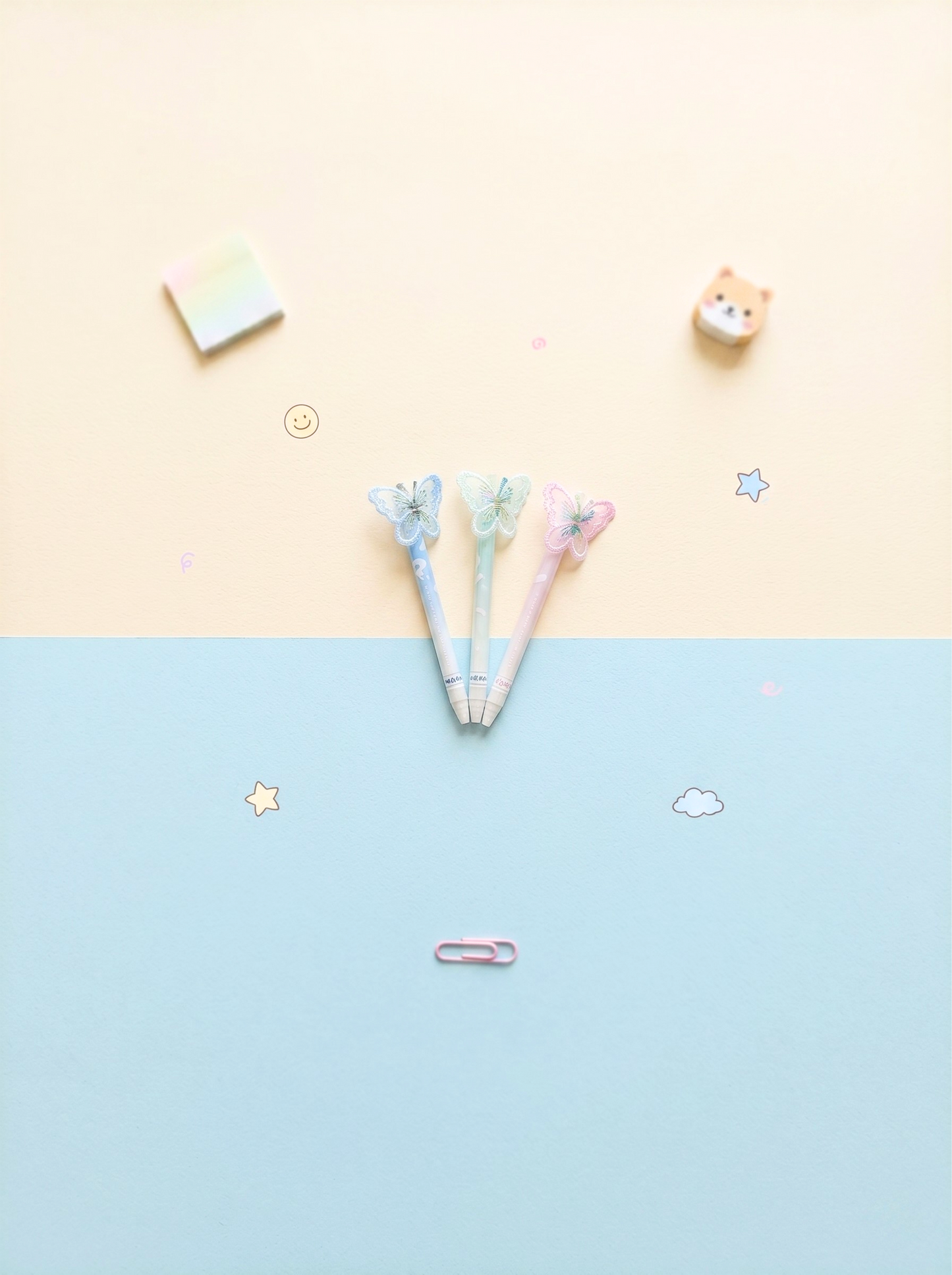 Three pens with decorative tops on a two-tone background with stickers.