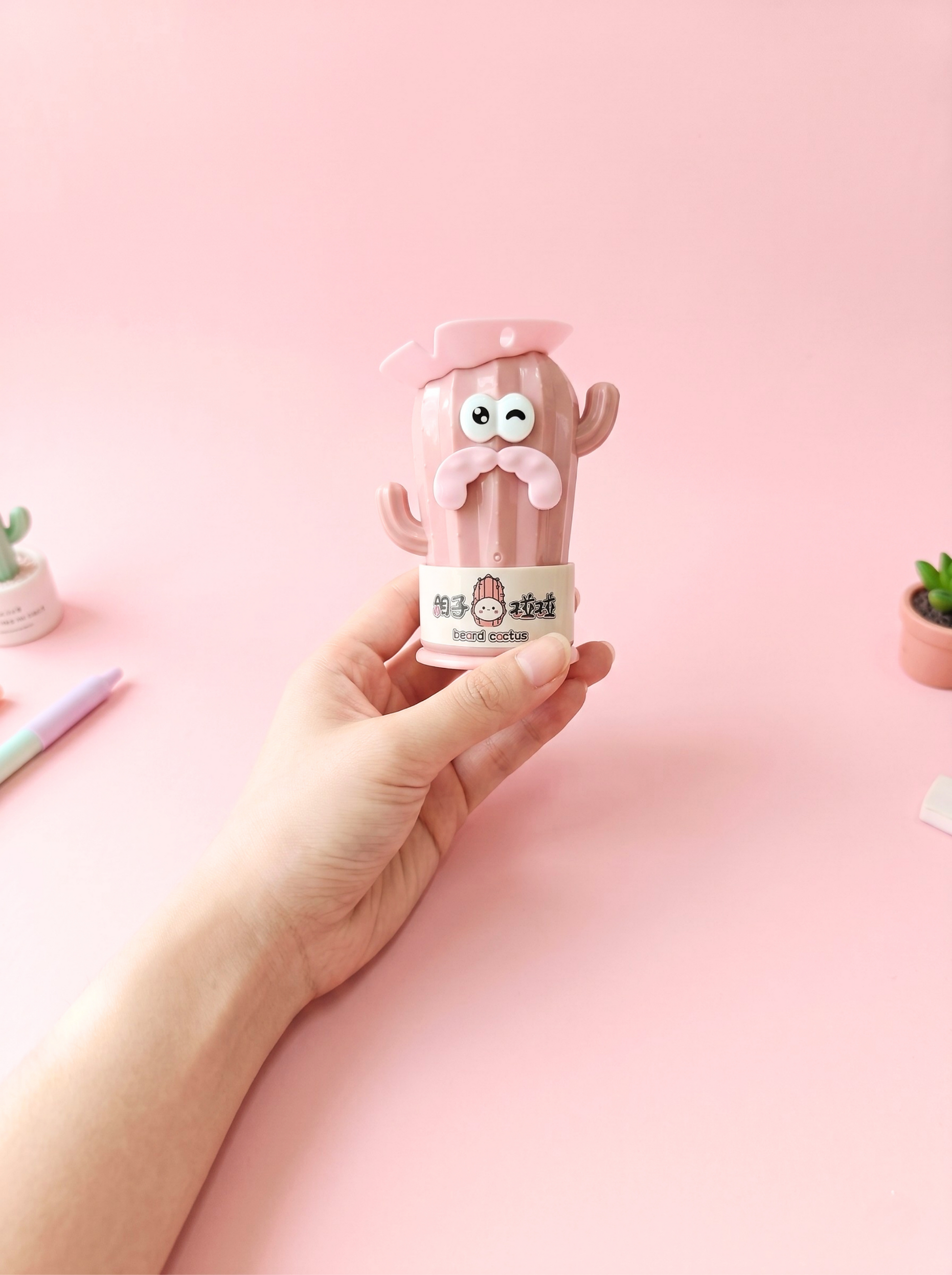 Cute pink cactus-shaped container with a face on a pink background