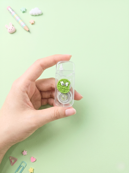 Hand holding a small green eraser with a face on a light green background