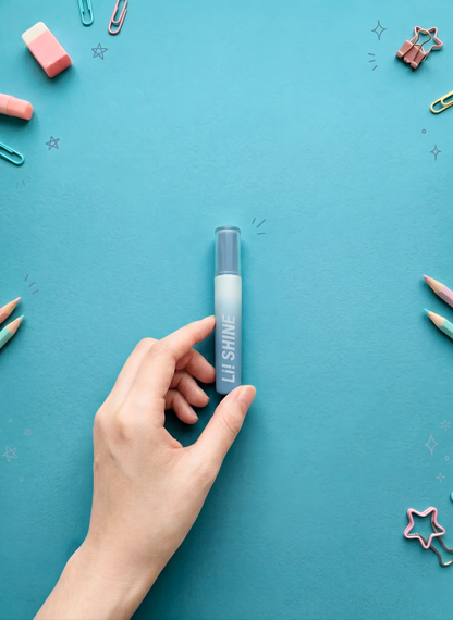 Hand holding a blue lip gloss tube on a teal background with decorative items.