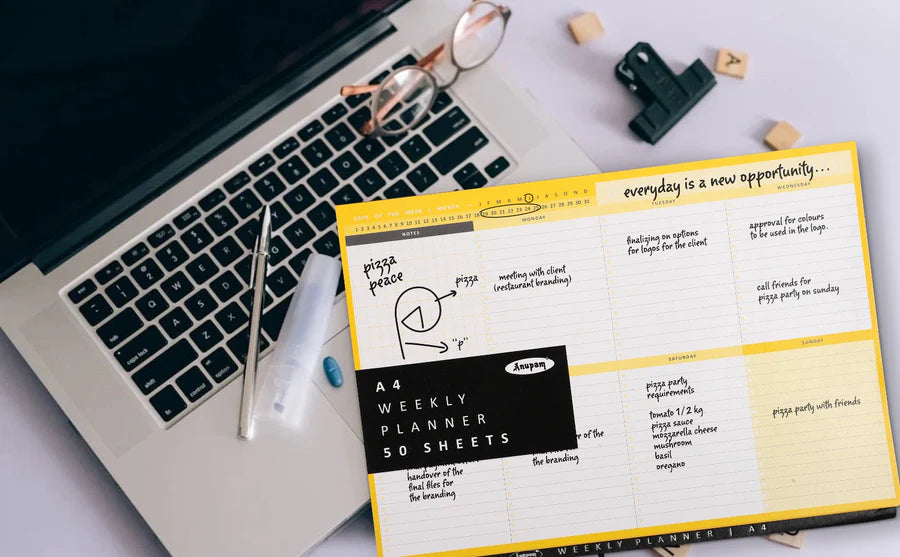 Weekly planner with motivational quote on a desk with laptop and stationery items