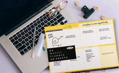 Weekly planner with motivational quote on a desk with laptop and stationery items