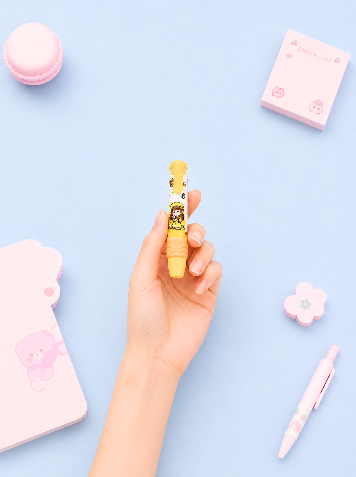Hand holding a small yellow toy with a pink background
