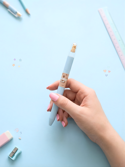 Hand holding a light blue pen with a wooden cap on a light blue background