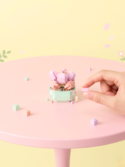 Small decorative plant on a pink table with a hand reaching towards it against a light yellow background