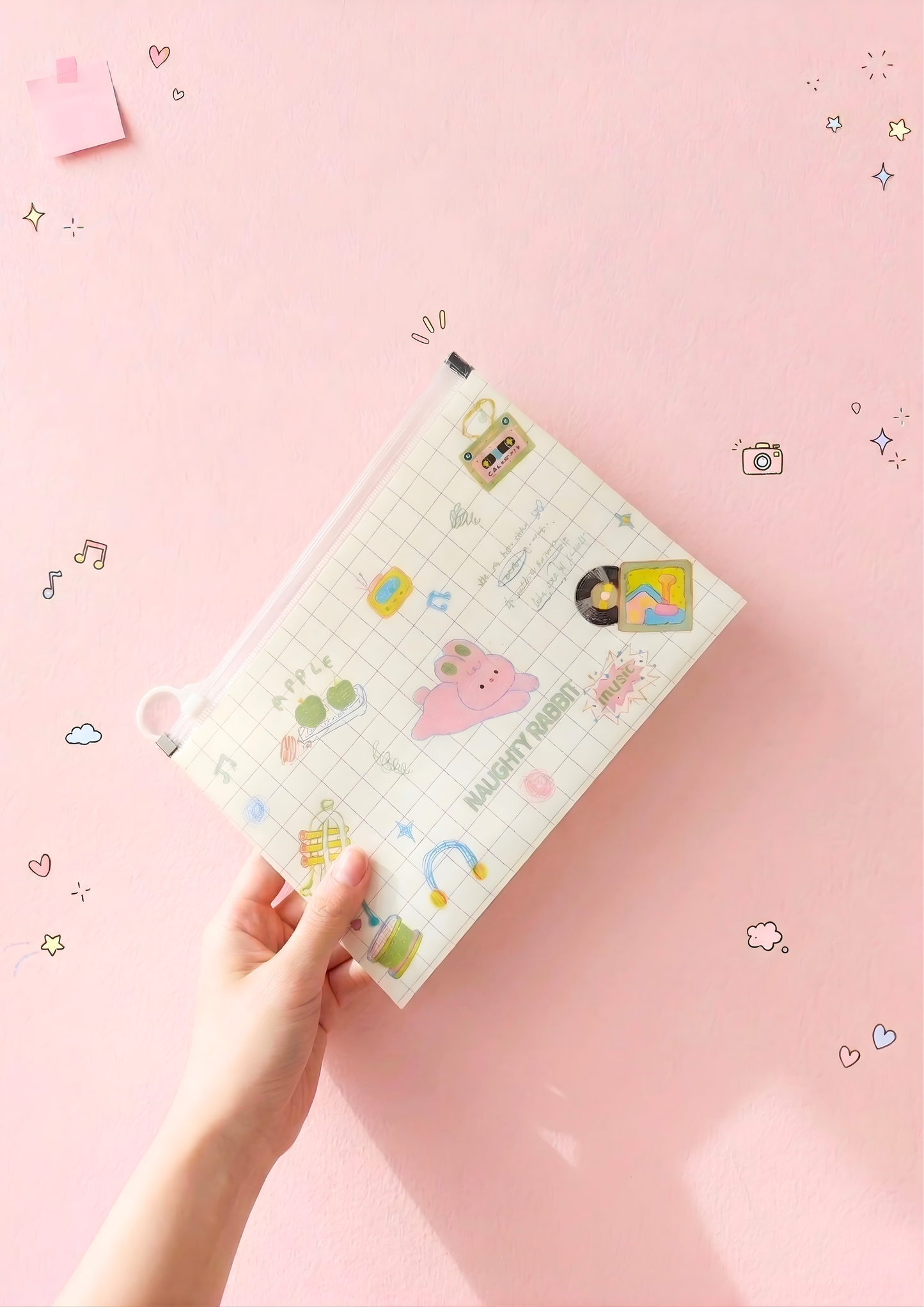 Hand holding a planner with cartoon designs on a pink background