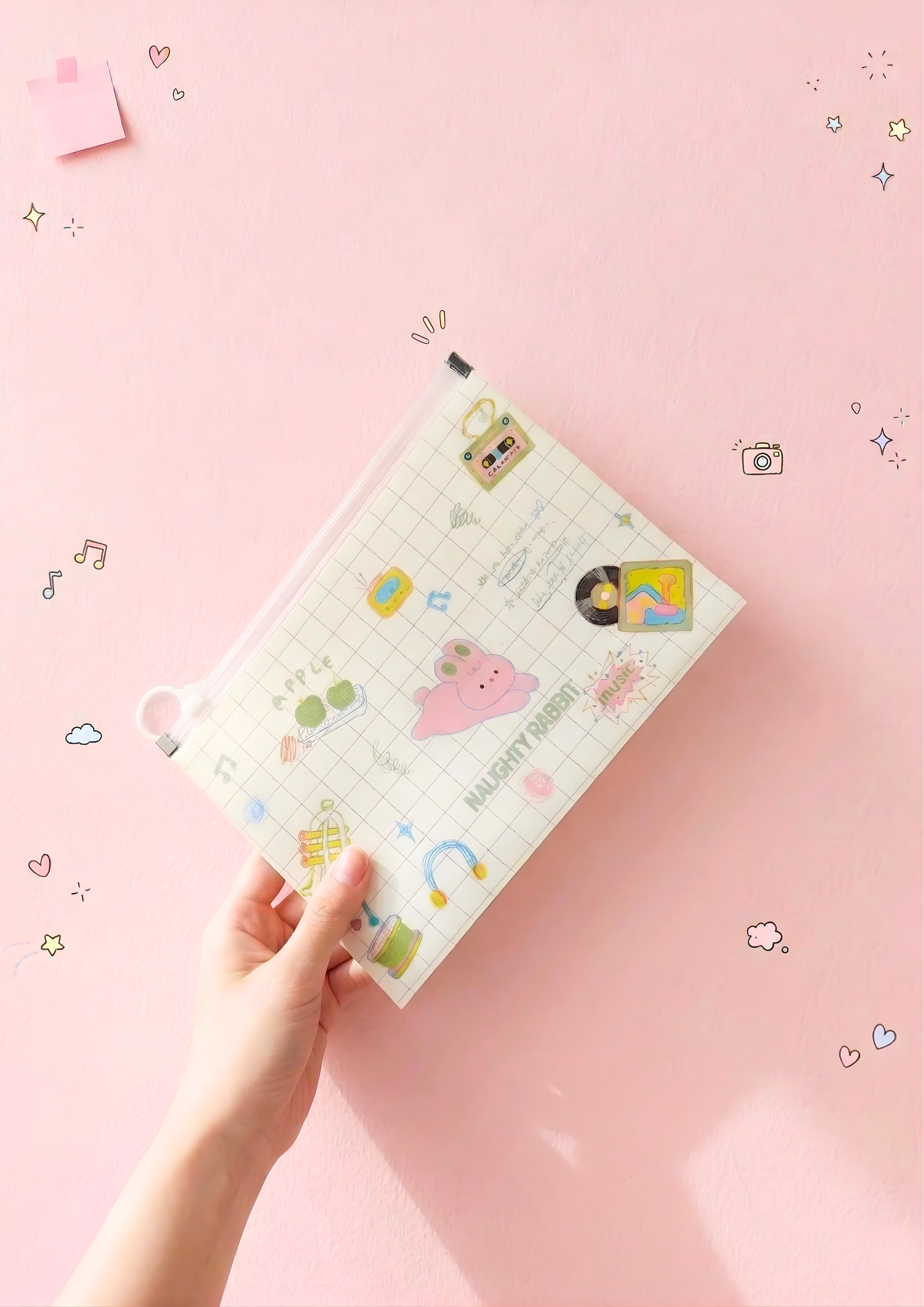 Hand holding a planner with cartoon designs on a pink background