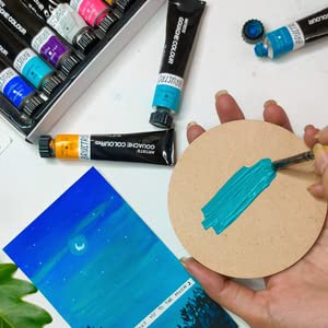 Art supplies including tubes of paint and a brush on a white surface.