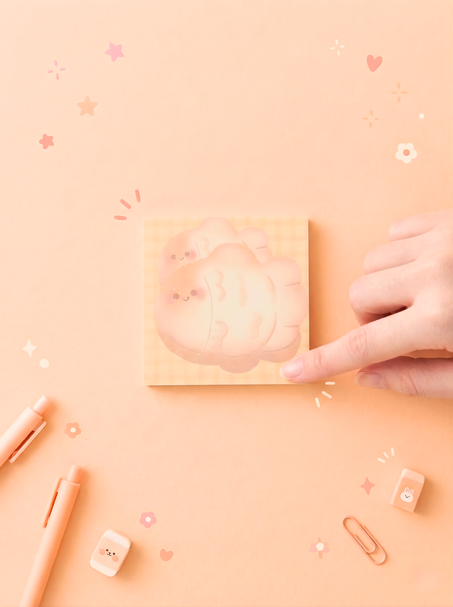 Hand holding a small pink notebook on a matching pink background with decorative elements.