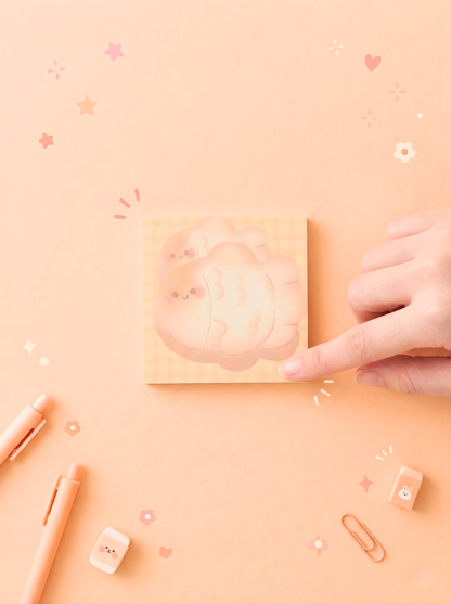 Hand holding a small pink notebook on a matching pink background with decorative elements.