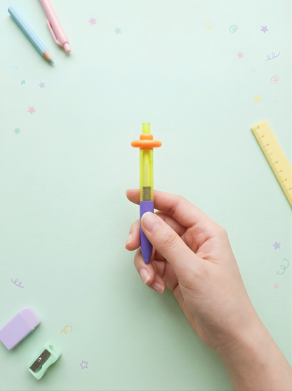 Hand holding a colorful pen with stationery items on a light green background