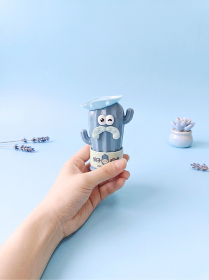Hand holding a small blue container with a cartoon character on a light blue background