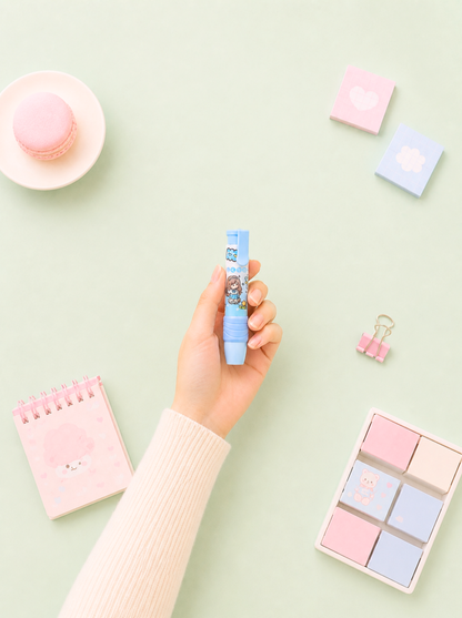 Hand holding a small blue container with stationery items on a light green background