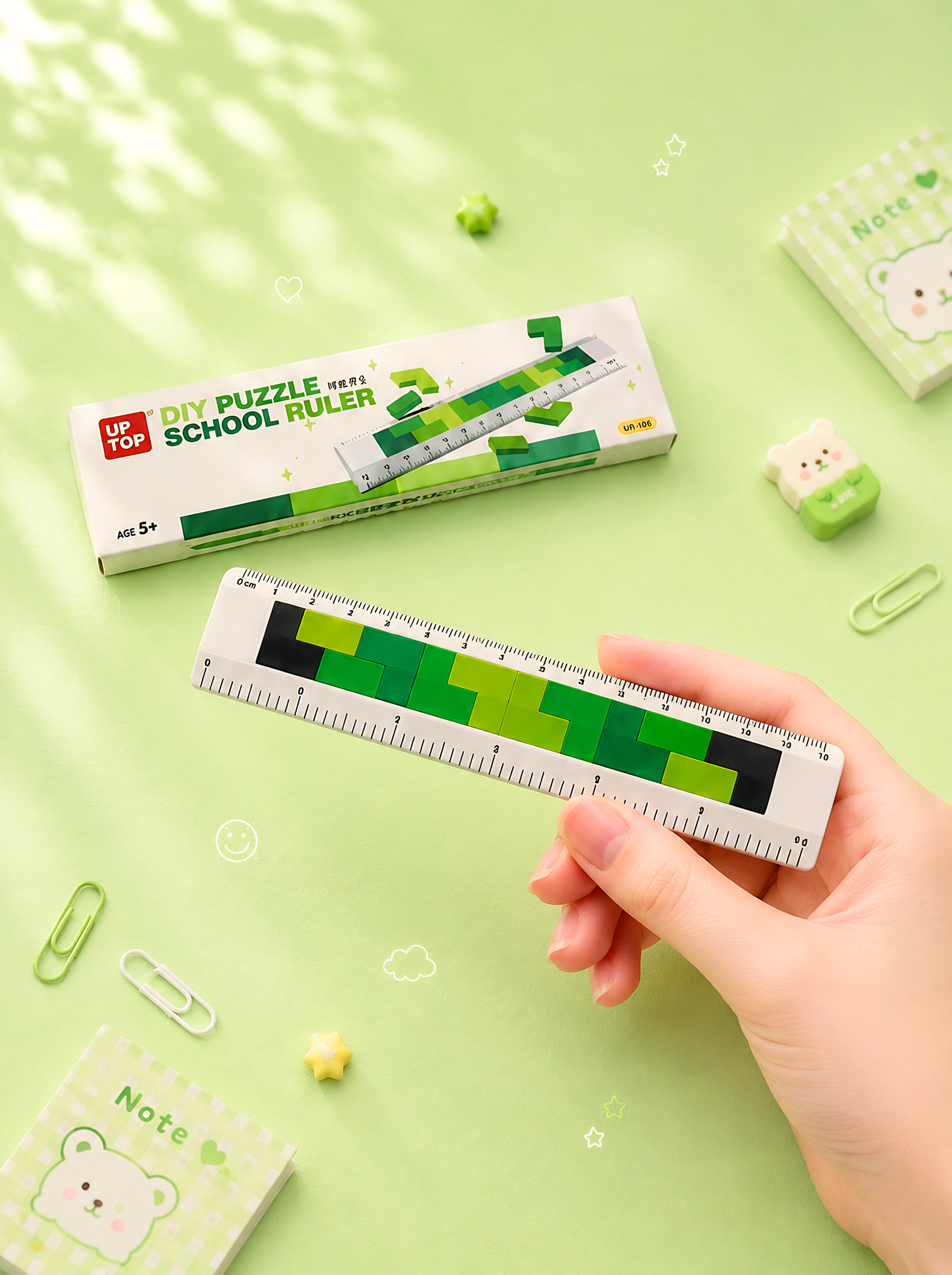 Hand holding a ruler with a green and black design on a light green background