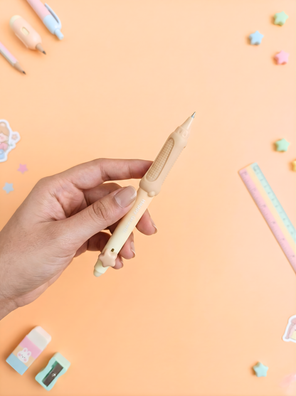 Hand holding a wooden pencil on a pastel pink background with stationery items.