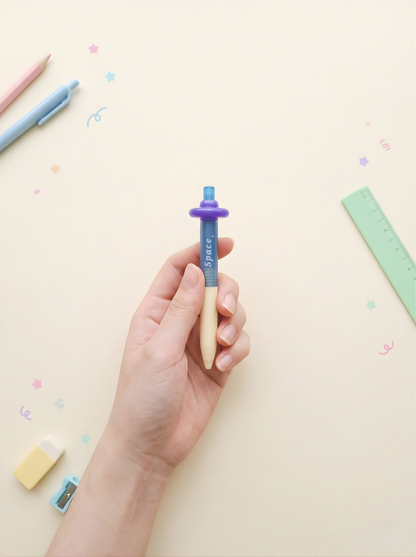 Hand holding a pen with colorful stationery items on a light background