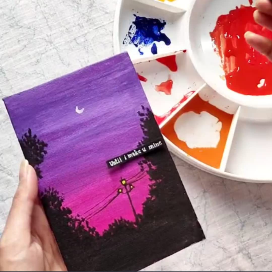 Hand-painted card with a purple and pink gradient and silhouette design, held over paint palettes.