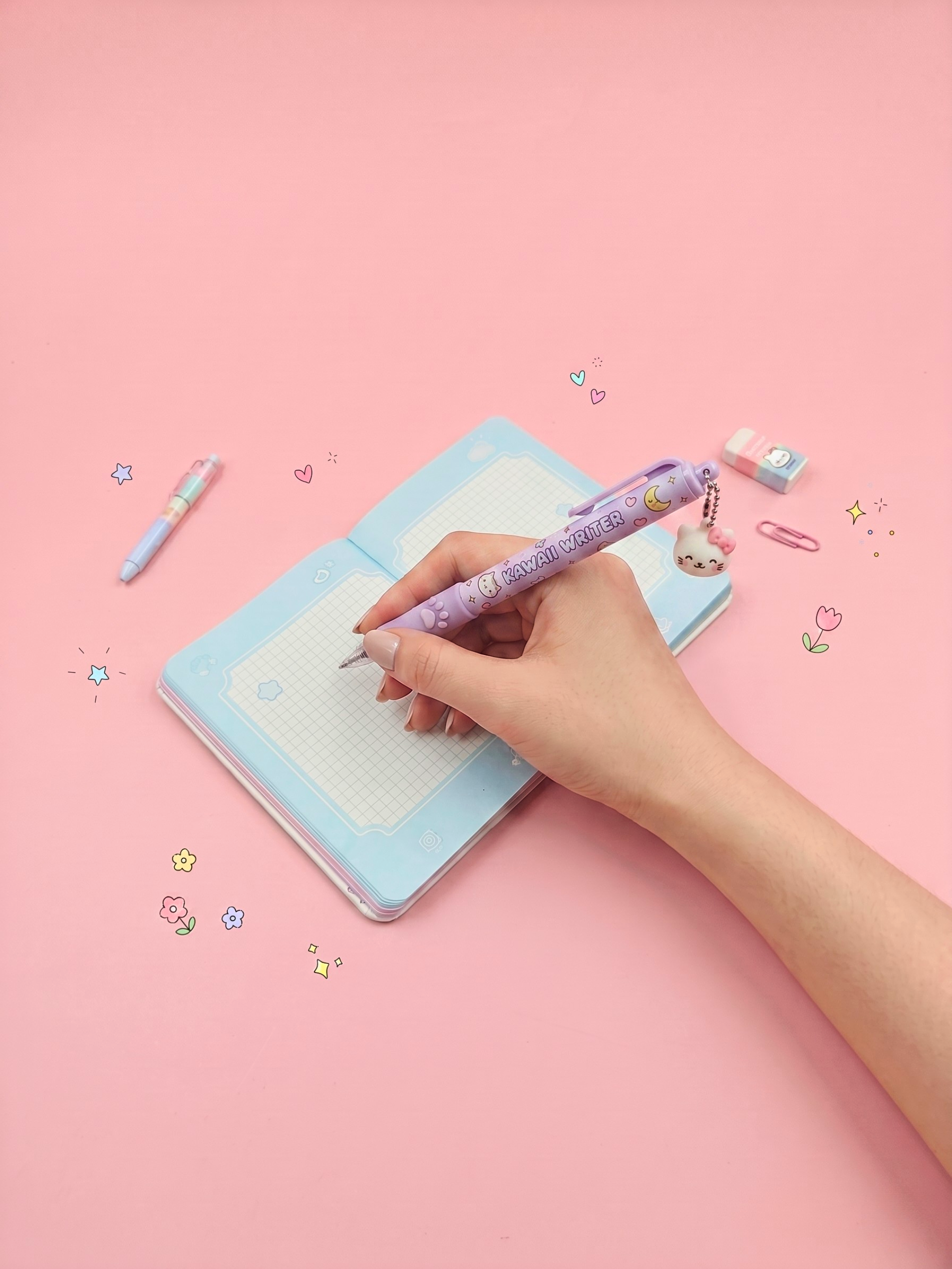 Hand writing in a light blue notebook with a purple pen on a pink background
