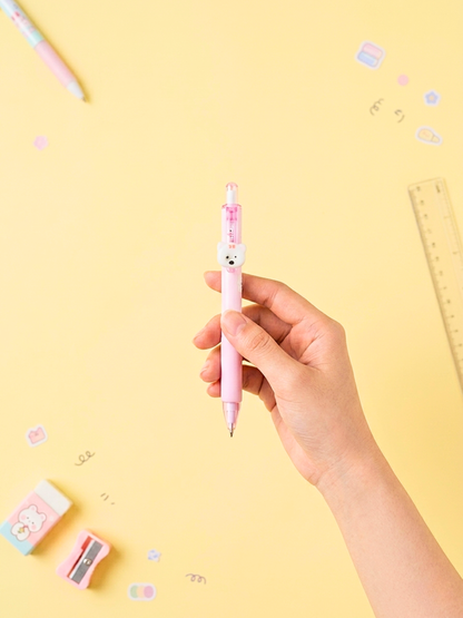 Hand holding a pink pen with a bear design on a yellow background