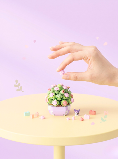 Small decorative plant on a yellow table with a hand reaching towards it against a light purple background