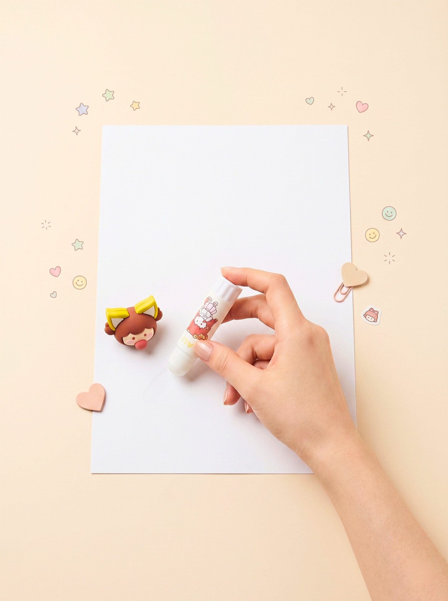 Hand holding a small bottle of nail polish next to a paper with a nail art design on a light beige background.