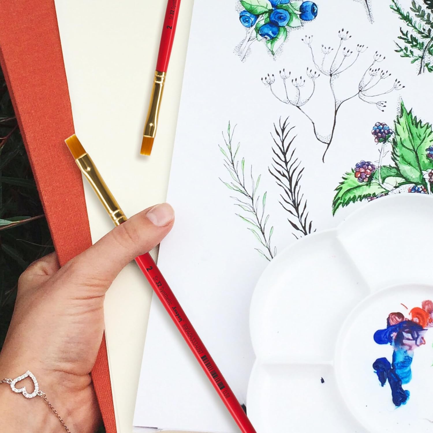 Artistic activity with colored pencils and a drawing of plants on a white surface.