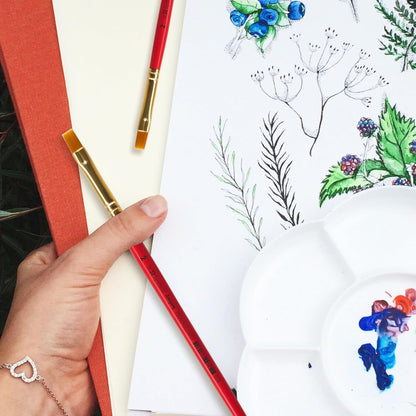 Artistic activity with colored pencils and a drawing of plants on a white surface.