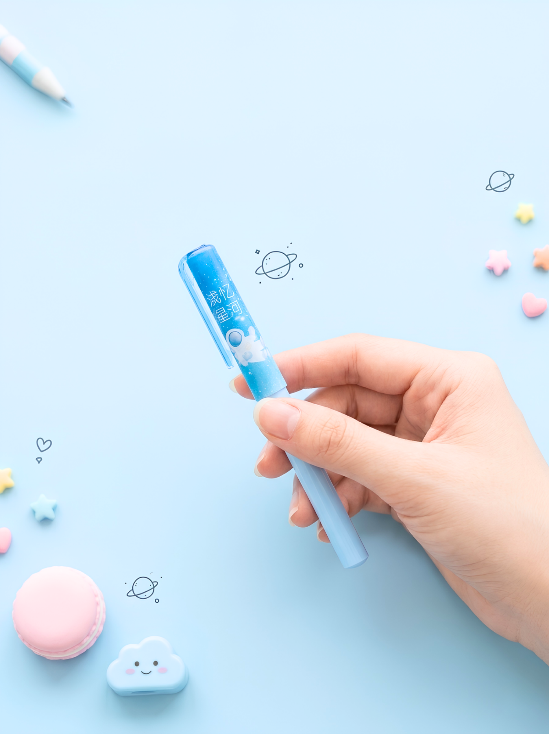 Hand holding a blue and white pen on a light blue background with decorative elements.