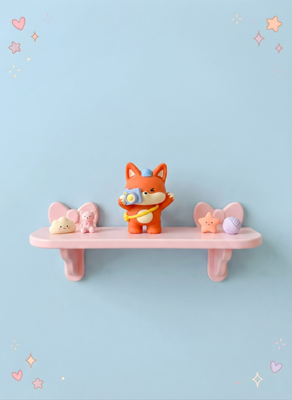Pink shelf with a cartoon fox figurine and two small animal figurines against a light blue background.