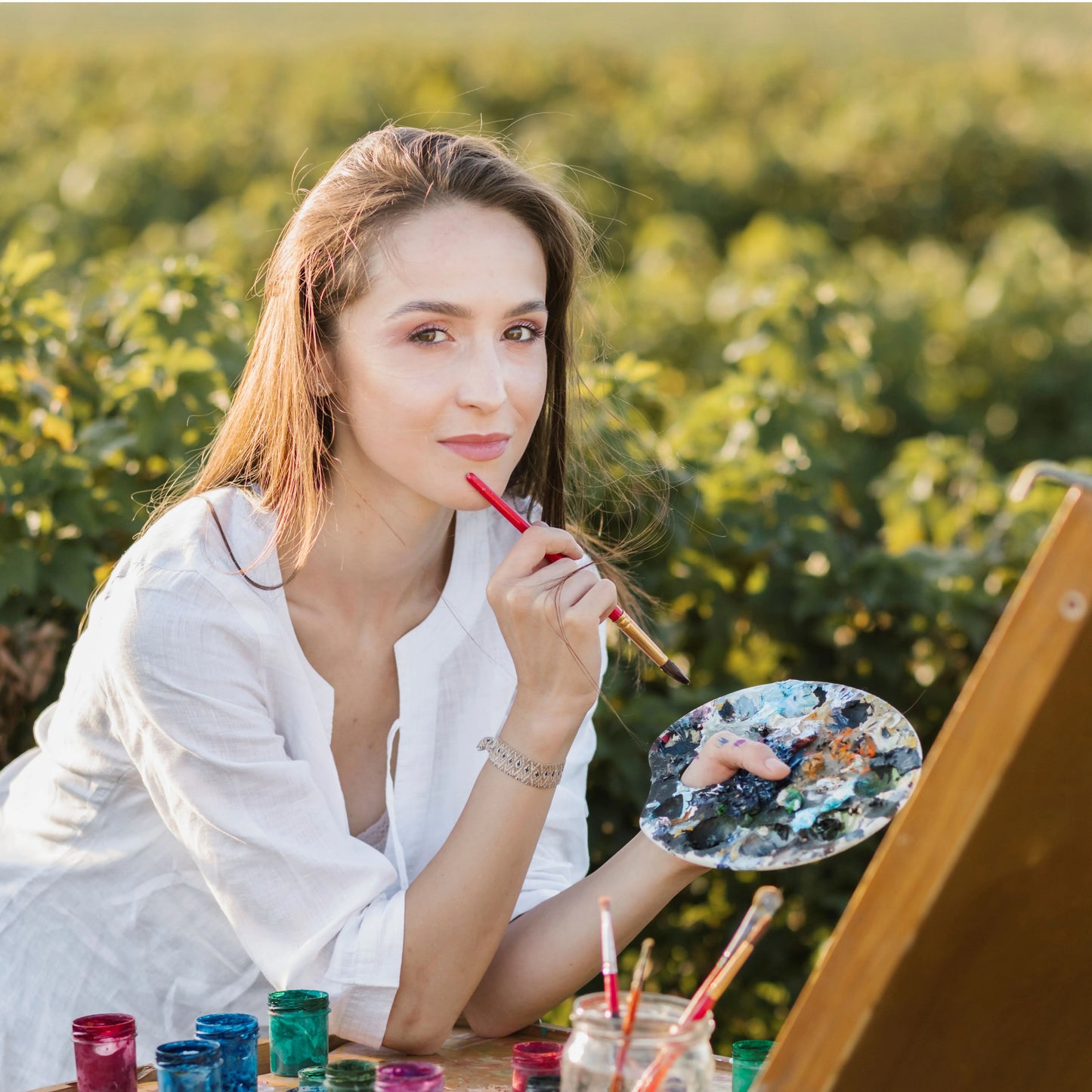 Woman painting outdoors with a field in the background