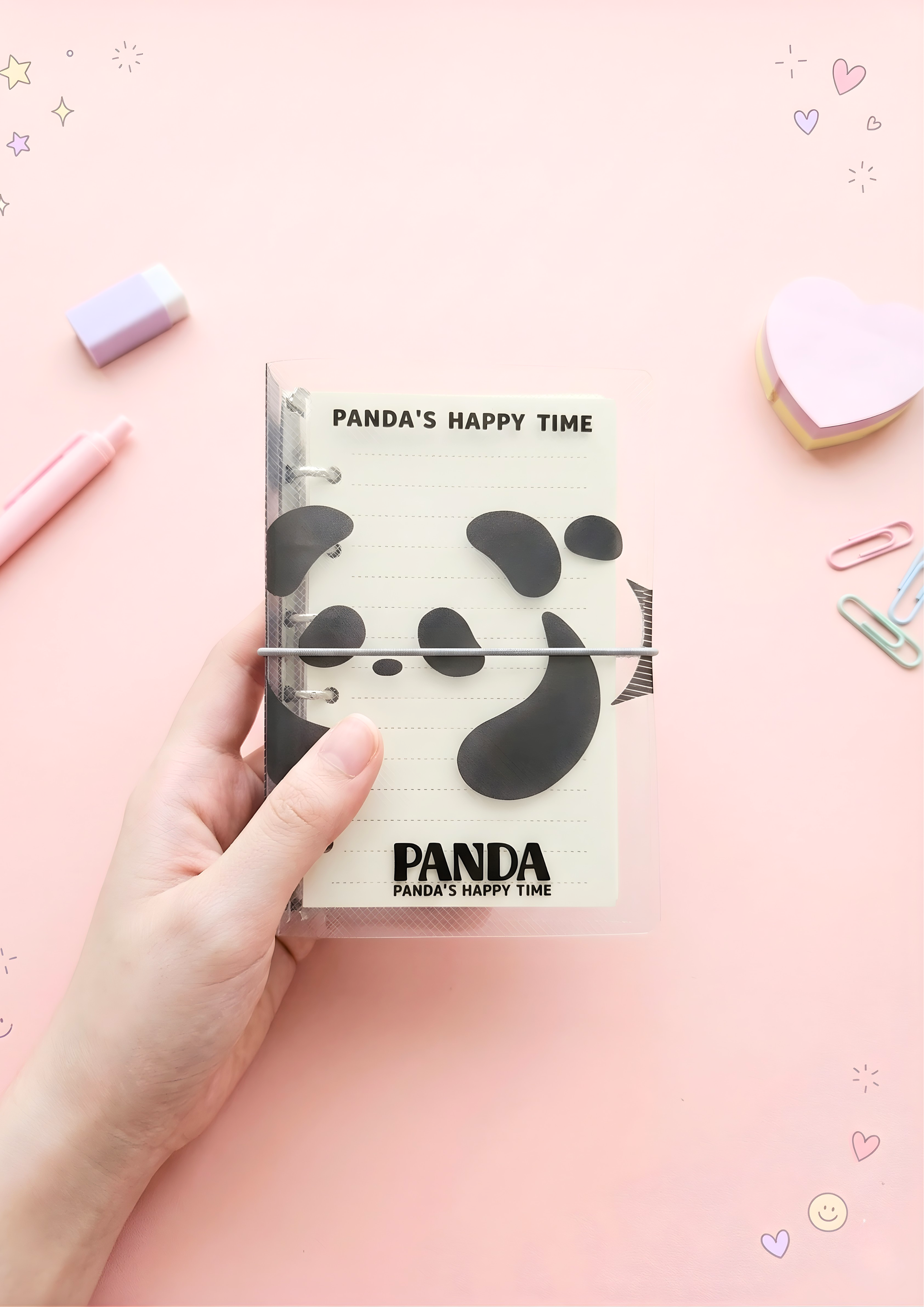 Notebook with panda design held by a hand on a pink background