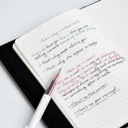 Open notebook with handwritten text and a pen on a white surface
