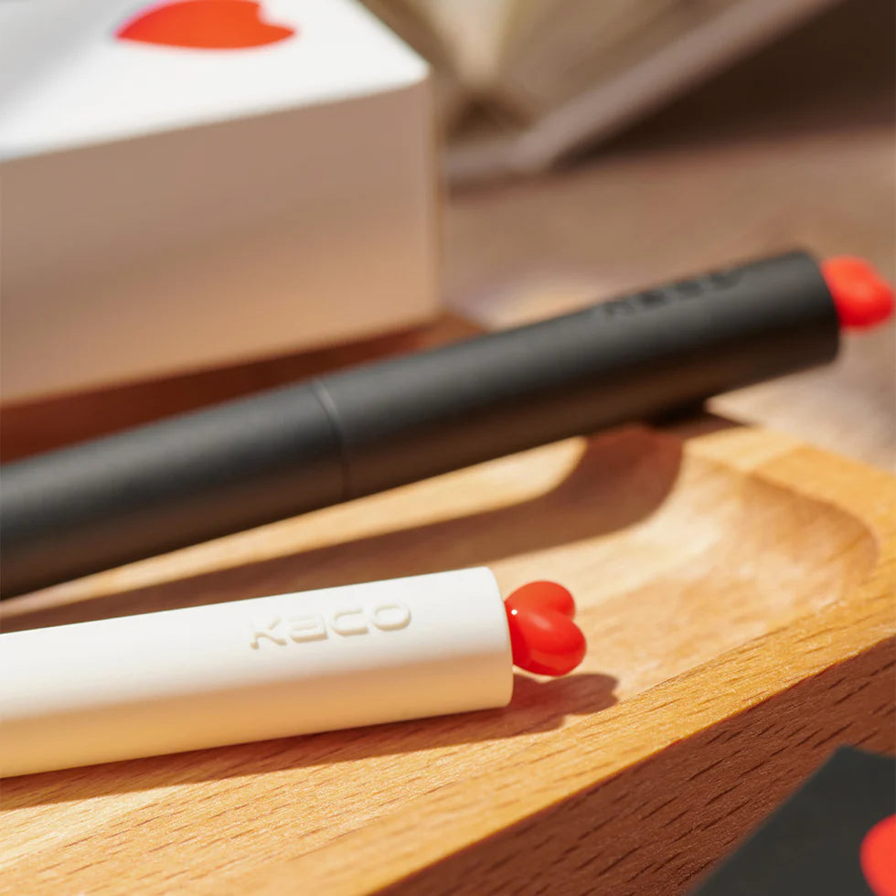 Two lip products with red caps on a wooden surface, one is open and the other is closed.