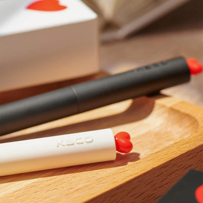 Two lip products with red caps on a wooden surface, one is open and the other is closed.