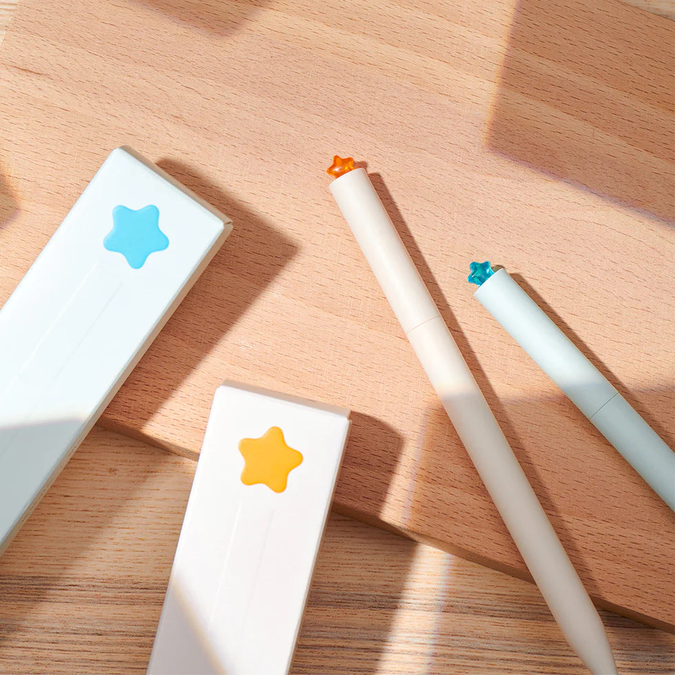 Two white pens with star-shaped tips on a wooden surface
