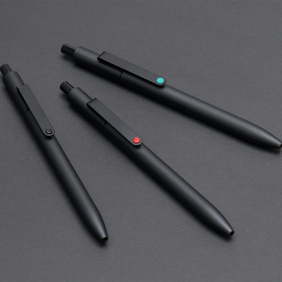 Three black pens with color-coded buttons on a gray surface