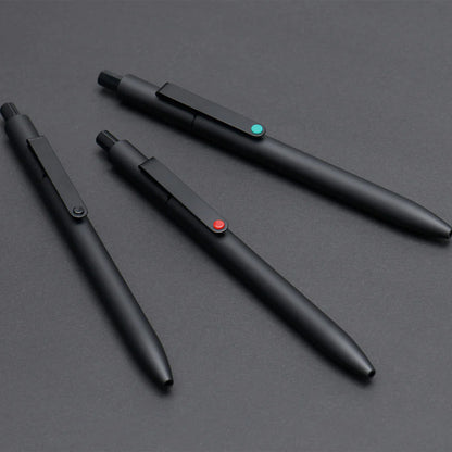 Three black pens with color-coded buttons on a gray surface