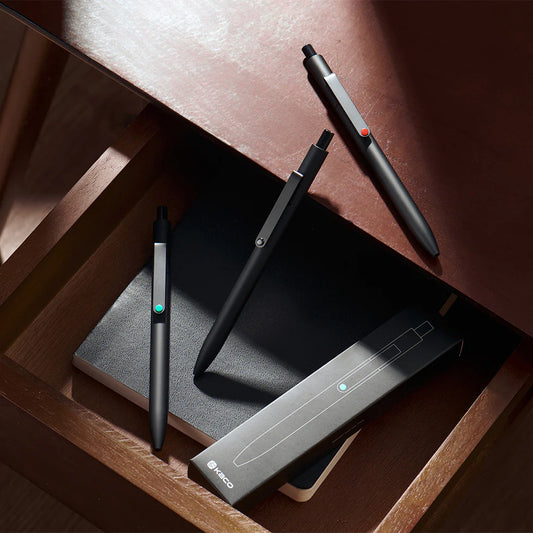 Three pens and a charging station on a wooden surface